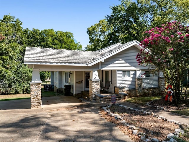 view of front of home with a carport, driveway, and stone siding