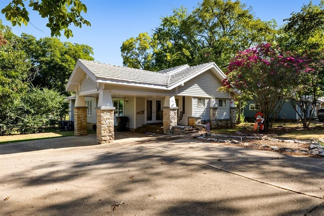 view of front facade with driveway, french doors, and stone siding