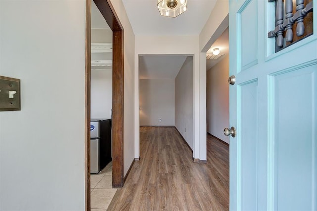 corridor with visible vents, baseboards, and light wood-style floors