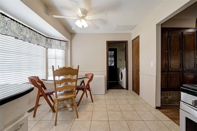 dining area with washer and dryer, light tile patterned floors, a wainscoted wall, and ceiling fan