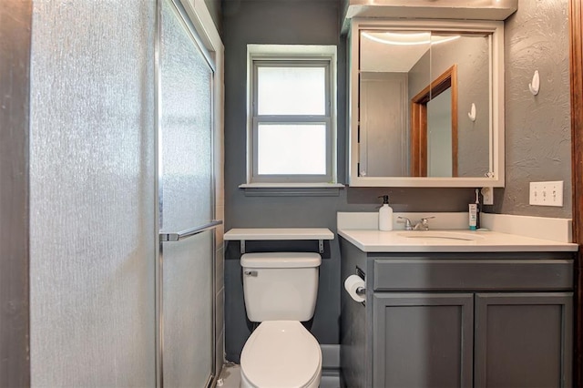 bathroom featuring toilet, vanity, and a shower stall
