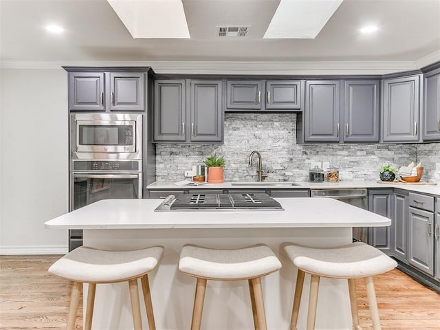 1804 Guilford Ln, Nichols Hills, OK 73120 - kitchen featuring a kitchen breakfast bar, gray cabinetry, visible vents, appliances with stainless steel finishes, and a sink