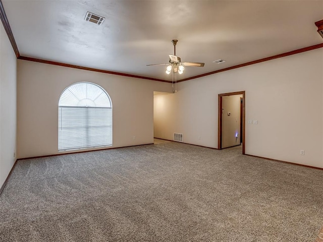 empty room featuring ornamental molding, a ceiling fan, carpet, and visible vents