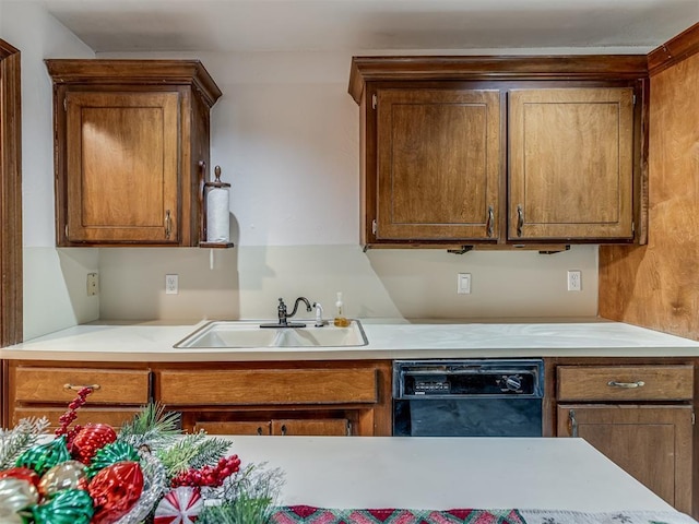 kitchen featuring light countertops, dishwasher, a sink, and brown cabinetry