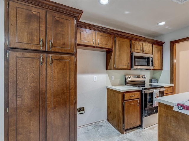 kitchen featuring baseboards, recessed lighting, light countertops, brown cabinets, and stainless steel appliances