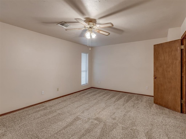 carpeted spare room with visible vents, ceiling fan, and baseboards