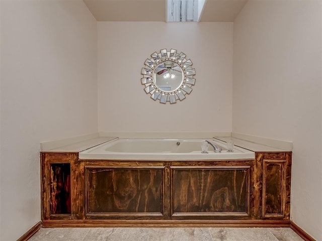 bathroom with a garden tub and baseboards
