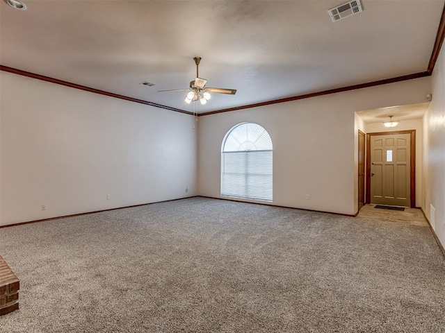 empty room featuring visible vents, light colored carpet, crown molding, and ceiling fan