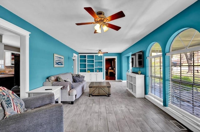 2315 Grisso Dr, Seminole, OK 74868 - living room featuring built in shelves, visible vents, a ceiling fan, and wood finished floors