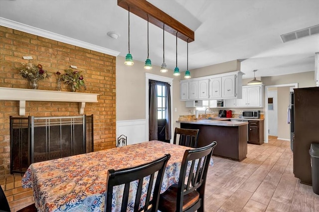 2315 Grisso Dr, Seminole, OK 74868 - dining room with visible vents, light wood finished floors, and a brick fireplace