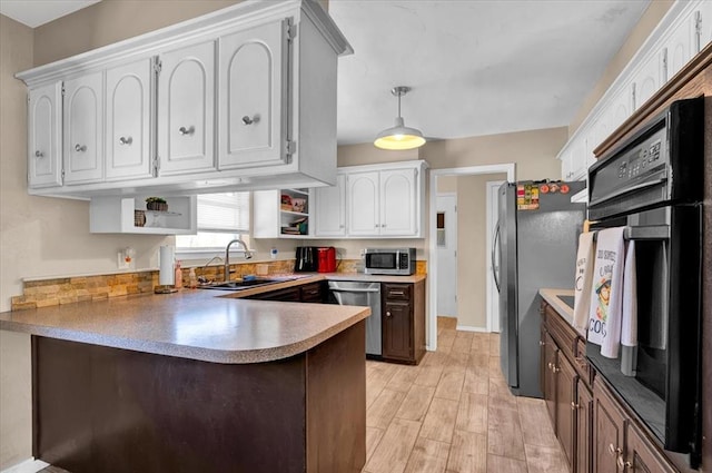2315 Grisso Dr, Seminole, OK 74868 - kitchen with a peninsula, open shelves, white cabinets, appliances with stainless steel finishes, and a sink
