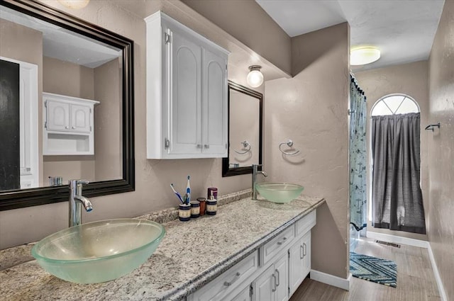 2315 Grisso Dr, Seminole, OK 74868 - bathroom featuring a textured wall, double vanity, a sink, and wood finished floors