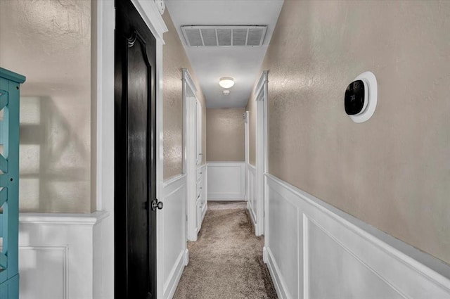 2315 Grisso Dr, Seminole, OK 74868 - corridor with a decorative wall, visible vents, a wainscoted wall, and light colored carpet