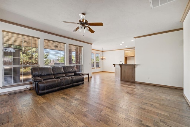 1240 Penny Ln, El Reno, OK 73036 - living area featuring ceiling fan with notable chandelier, wood-type flooring, crown molding, visible vents, and baseboards