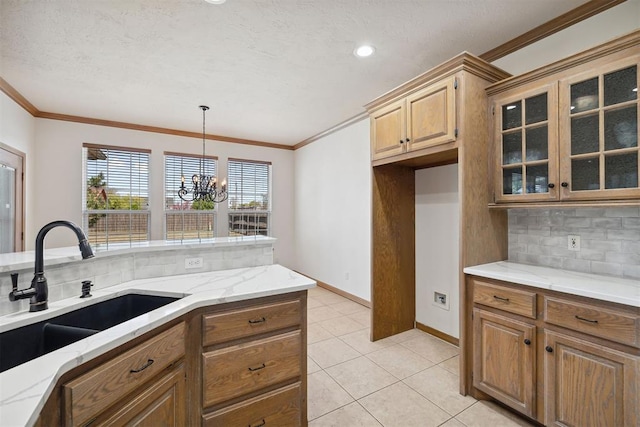 1240 Penny Ln, El Reno, OK 73036 - kitchen featuring a sink, ornamental molding, an inviting chandelier, backsplash, and light stone countertops