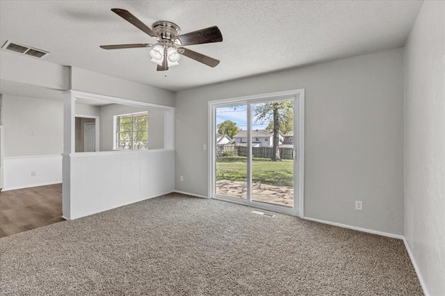 spare room with a textured ceiling, carpet, visible vents, and a ceiling fan