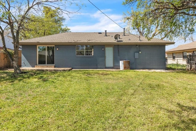 back of house with brick siding, fence, and a lawn