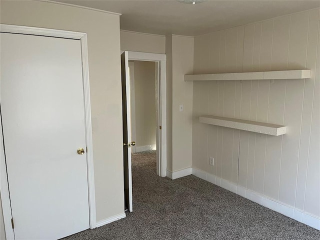 interior space with baseboards and dark carpet