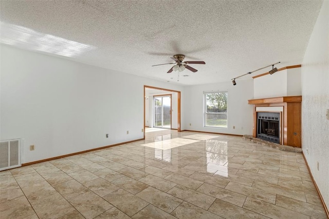 unfurnished living room featuring a fireplace with raised hearth, visible vents, a textured ceiling, and ceiling fan