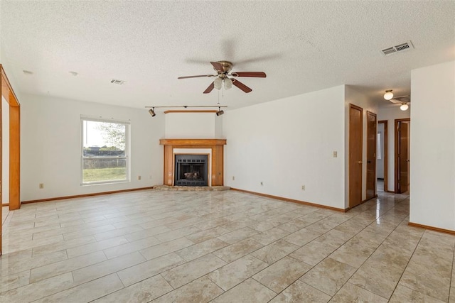 unfurnished living room featuring a textured ceiling, visible vents, a ceiling fan, and a fireplace with raised hearth