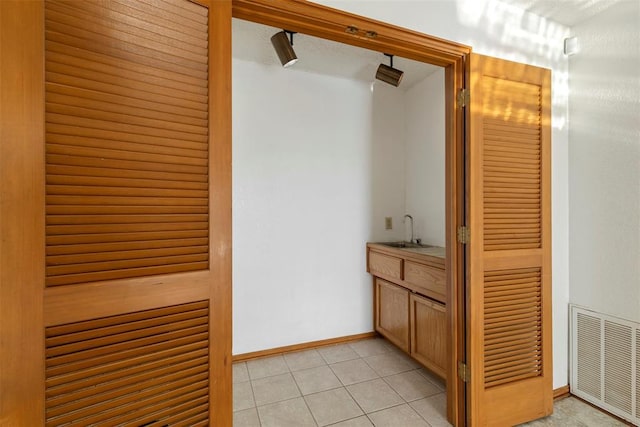 bathroom featuring tile patterned floors, visible vents, baseboards, and a sink
