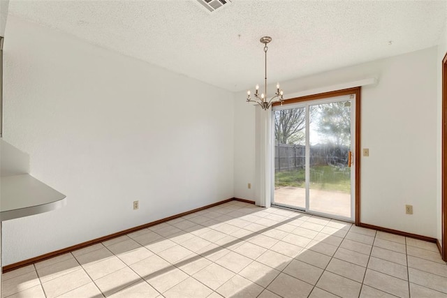 unfurnished dining area featuring a textured ceiling, an inviting chandelier, and light tile patterned floors