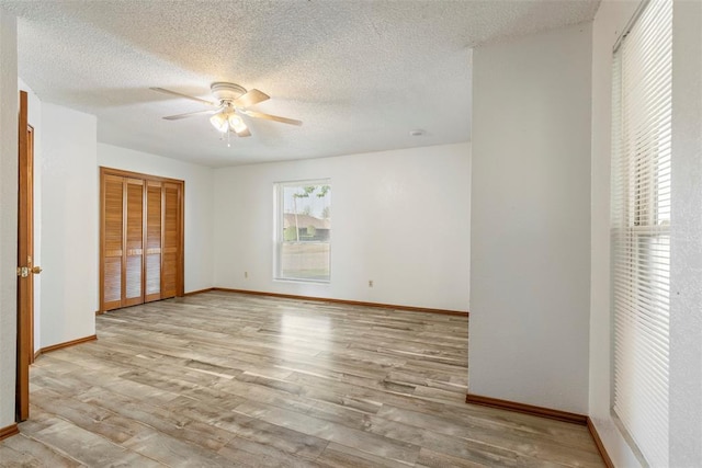unfurnished bedroom featuring a closet, baseboards, wood finished floors, and a textured ceiling
