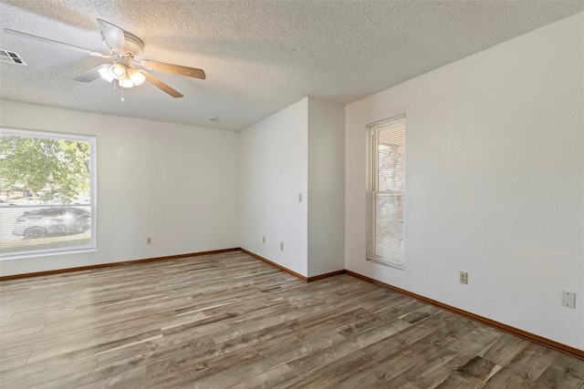 spare room with visible vents, a textured ceiling, a ceiling fan, and wood finished floors