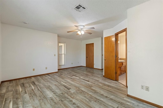 spare room featuring light wood-style floors, ceiling fan, a textured ceiling, visible vents, and baseboards