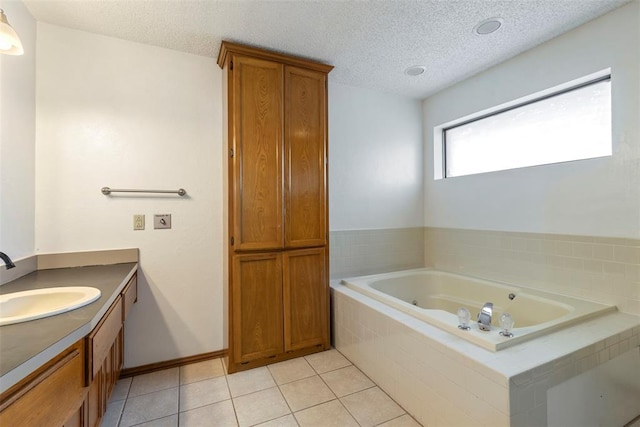 full bath featuring a textured ceiling, vanity, a whirlpool tub, and tile patterned floors