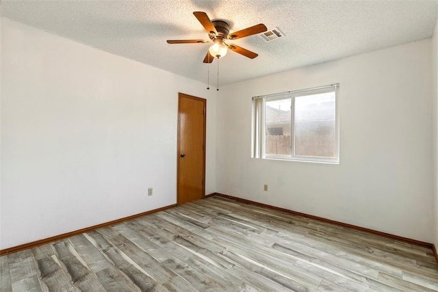 unfurnished room featuring baseboards, a textured ceiling, a ceiling fan, visible vents, and light wood finished floors