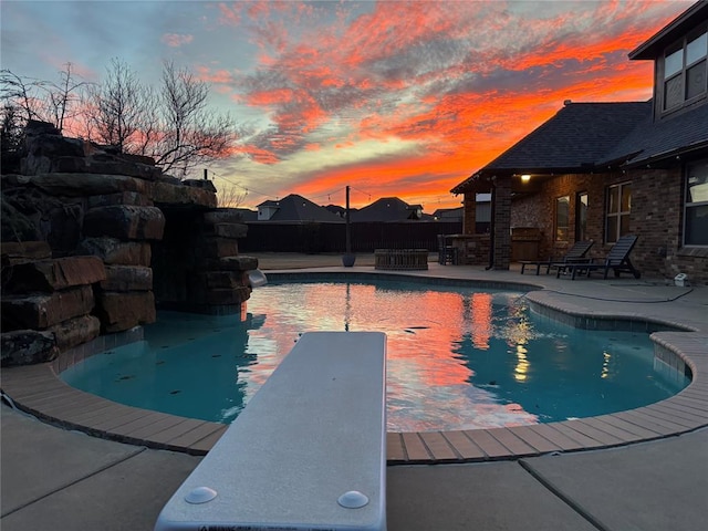 view of swimming pool featuring a diving board, a fenced in pool, a fenced backyard, and a patio area