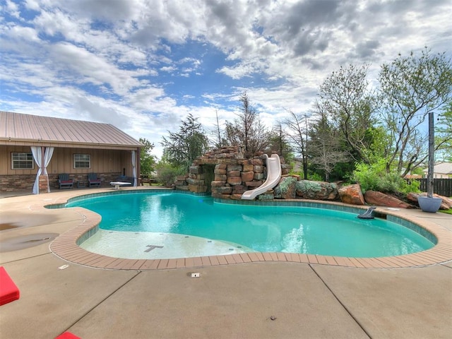 outdoor pool featuring a water slide, a diving board, and a patio area