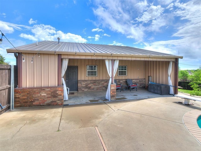 back of property featuring brick siding, board and batten siding, and fence