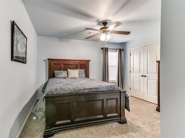 bedroom with a closet, ceiling fan, light carpet, and baseboards