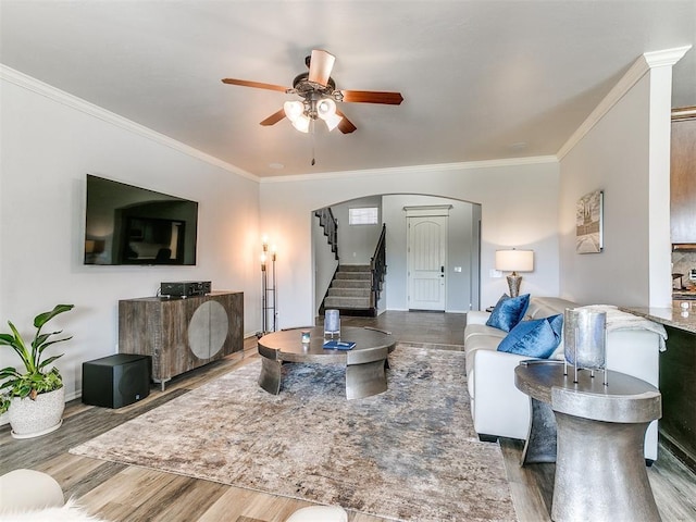 living area featuring stairway, wood finished floors, ceiling fan, and ornamental molding