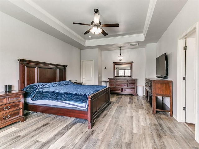 bedroom featuring visible vents, ornamental molding, light wood-style floors, and a tray ceiling