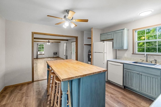 kitchen with a sink, a ceiling fan, white appliances, light wood-style floors, and wood counters