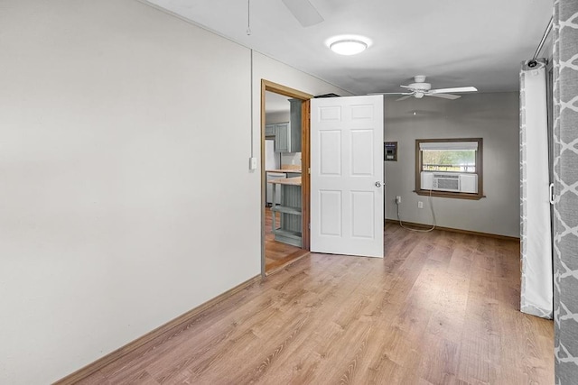 spare room with ceiling fan, light wood-type flooring, cooling unit, and baseboards