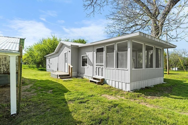 back of property featuring a sunroom and a lawn