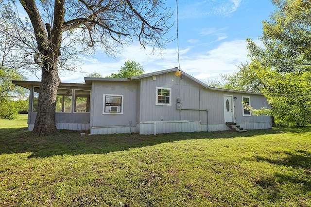 rear view of property featuring a yard, entry steps, and a sunroom