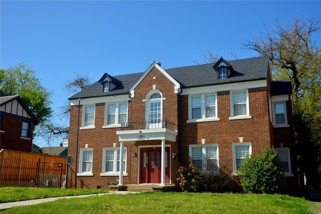 colonial inspired home featuring brick siding, fence, and a front yard