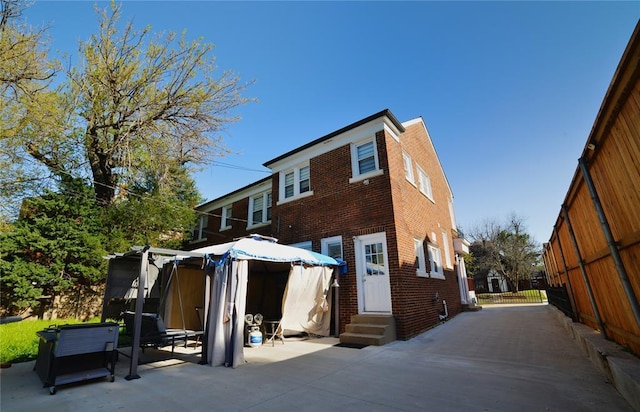 rear view of house featuring brick siding, a patio area, and entry steps