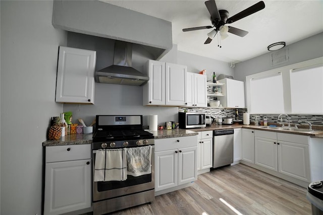 kitchen featuring a sink, wall chimney exhaust hood, backsplash, and stainless steel appliances