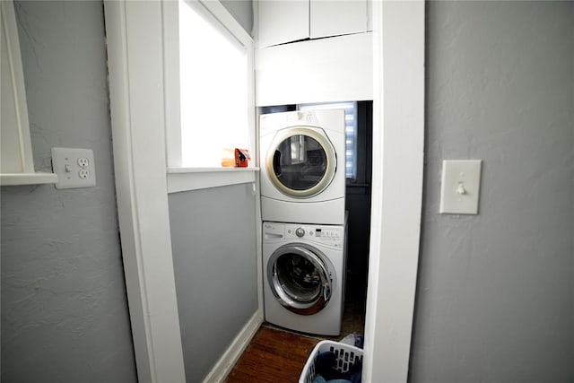 clothes washing area featuring stacked washer and dryer, laundry area, and dark wood-style floors