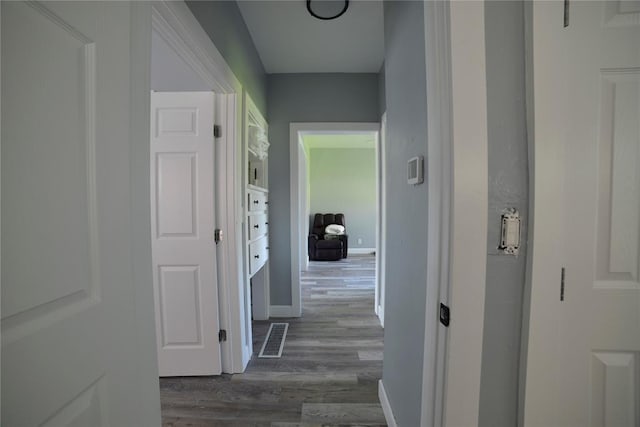 hall featuring dark wood-type flooring, baseboards, and visible vents