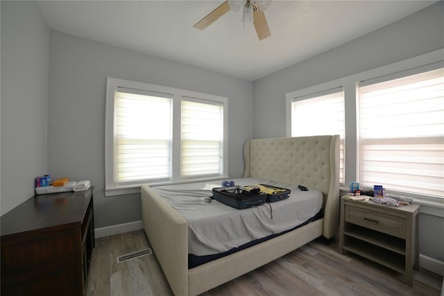 bedroom with ceiling fan, baseboards, visible vents, and wood finished floors