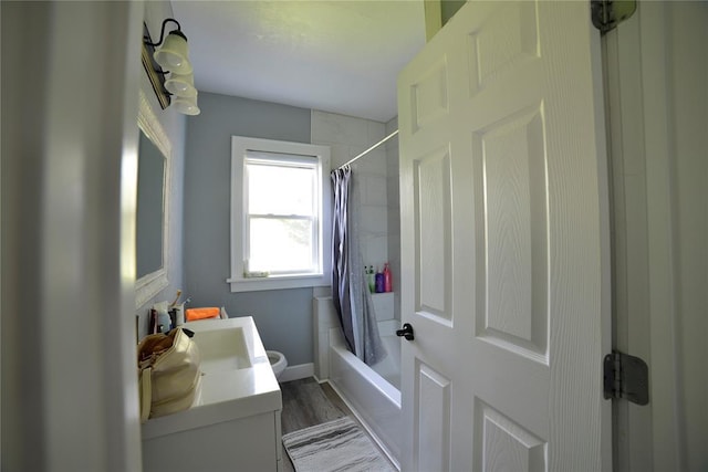 bathroom featuring toilet, wood finished floors, shower / tub combo, and vanity