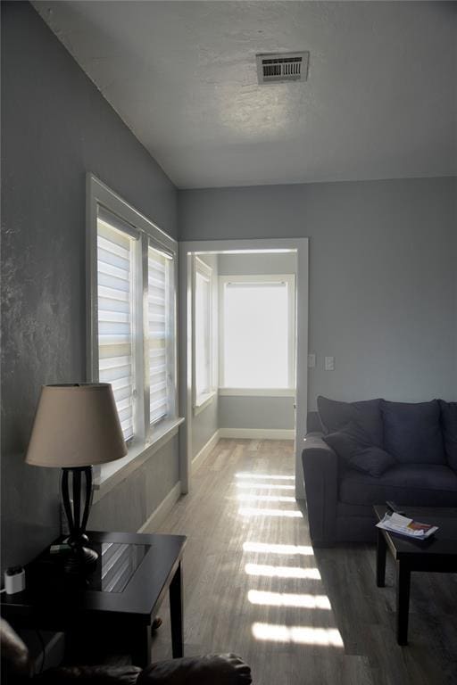 living room with baseboards, visible vents, and wood finished floors