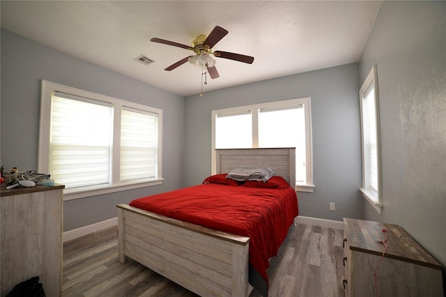 bedroom with baseboards, ceiling fan, wood finished floors, and visible vents